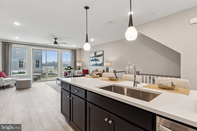 kitchen featuring stainless steel dishwasher, light countertops, open floor plan, and a sink