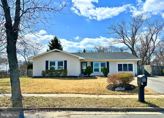 ranch-style house with aphalt driveway, a front yard, a chimney, and fence