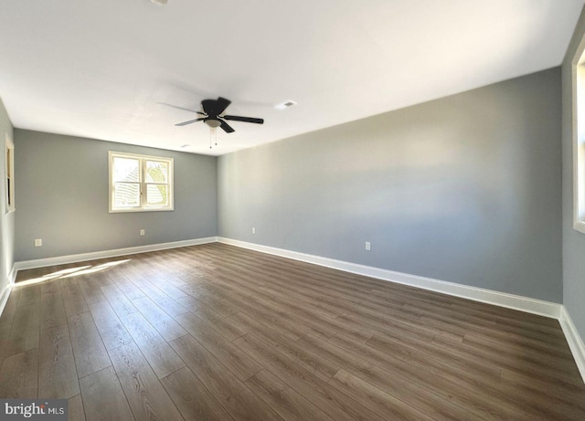 empty room with visible vents, baseboards, dark wood-style floors, and a ceiling fan