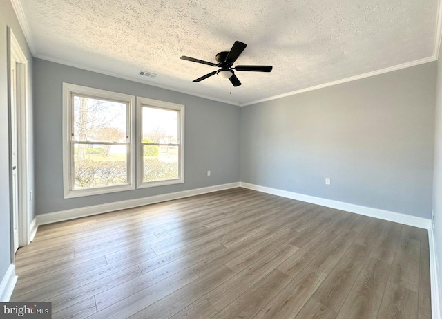 spare room featuring crown molding, wood finished floors, visible vents, and baseboards