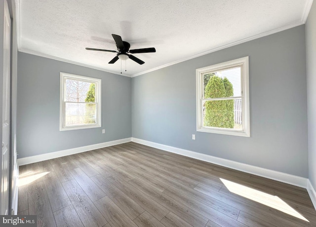 spare room featuring dark wood finished floors, a textured ceiling, crown molding, and baseboards