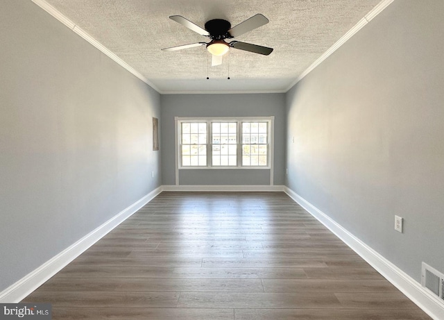 spare room featuring visible vents, crown molding, dark wood-type flooring, and baseboards