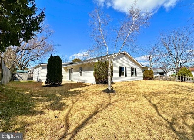 rear view of property featuring a yard and fence