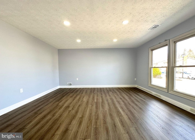 unfurnished room with baseboards, visible vents, and dark wood-style flooring