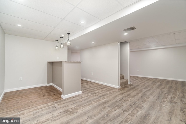 finished basement featuring visible vents, baseboards, wood finished floors, and stairway