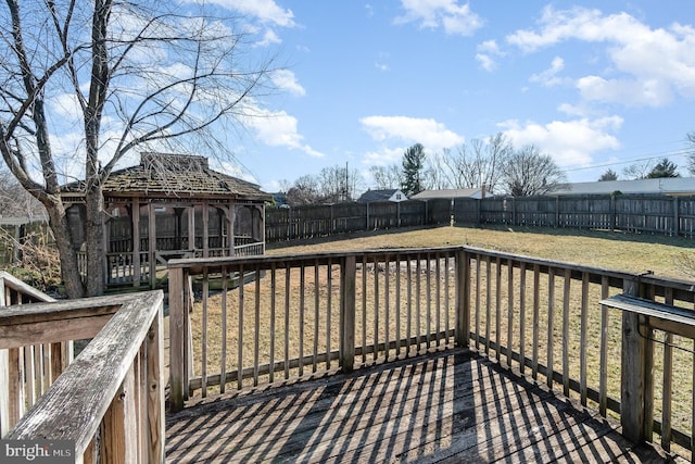 wooden terrace featuring a gazebo, a lawn, and a fenced backyard