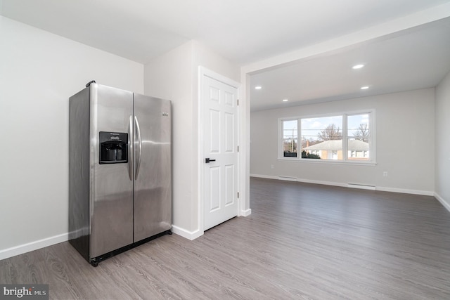 kitchen with baseboards, wood finished floors, stainless steel refrigerator with ice dispenser, and a baseboard radiator