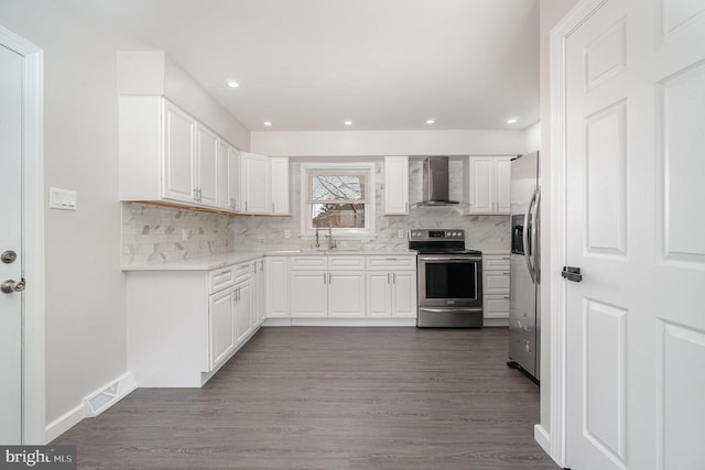 kitchen with dark wood-style floors, appliances with stainless steel finishes, wall chimney exhaust hood, and decorative backsplash