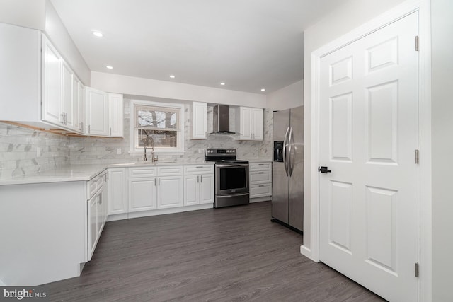 kitchen with a sink, wall chimney range hood, stainless steel appliances, white cabinetry, and dark wood-style flooring