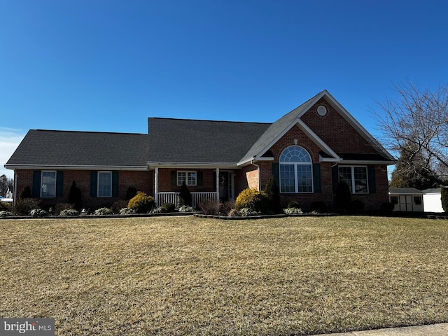 view of front facade with brick siding, a shed, an outdoor structure, and a front lawn