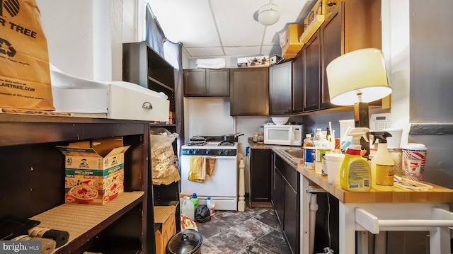 kitchen featuring beverage cooler, dark brown cabinets, white appliances, and a paneled ceiling