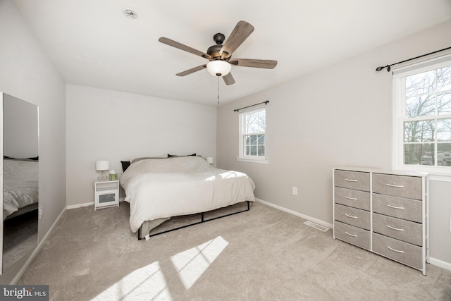 bedroom featuring visible vents, light carpet, baseboards, and ceiling fan