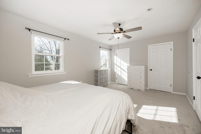 bedroom with light colored carpet, a ceiling fan, and baseboards