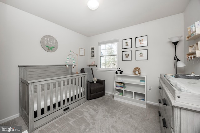 bedroom featuring baseboards, a nursery area, and carpet flooring