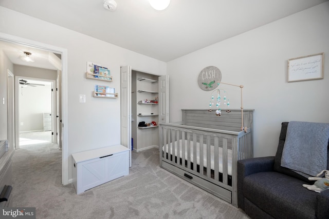 bedroom featuring baseboards, light carpet, and a crib