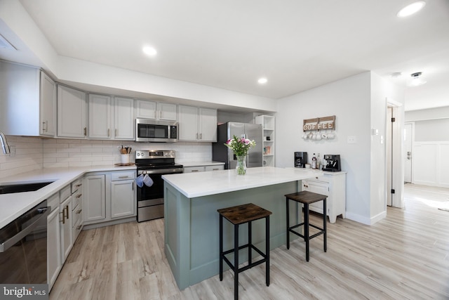 kitchen with tasteful backsplash, a kitchen island, a breakfast bar, appliances with stainless steel finishes, and a sink