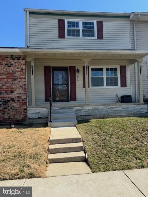 view of front of property featuring a porch, brick siding, and a front lawn