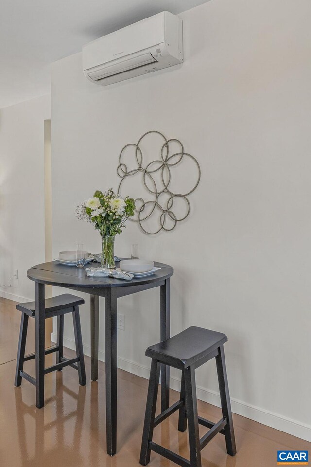 dining area featuring baseboards and an AC wall unit