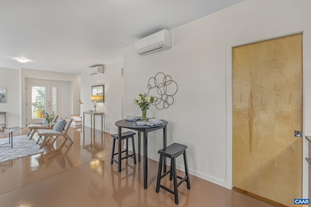 interior space with finished concrete floors, a wall mounted AC, and baseboards