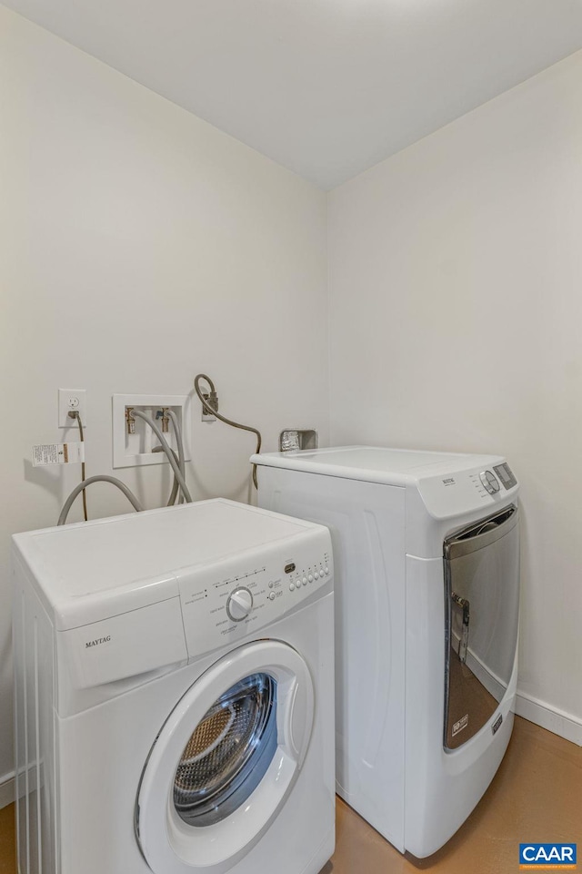 clothes washing area with washer and dryer, baseboards, and laundry area