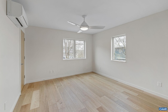 unfurnished room with light wood-style flooring, plenty of natural light, a ceiling fan, and a wall mounted air conditioner