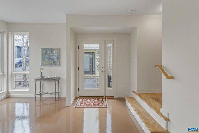 entrance foyer with stairs, finished concrete flooring, and baseboards