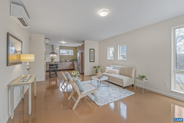 living area featuring a wall mounted air conditioner, baseboards, finished concrete floors, and a wall mounted AC