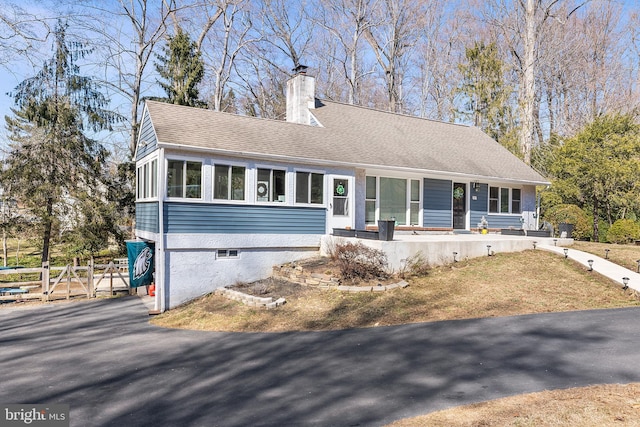 view of front of property with a chimney, roof with shingles, and a sunroom