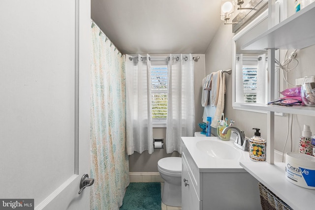 bathroom featuring toilet, vanity, and baseboards