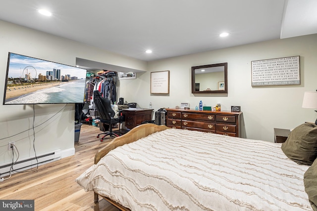 bedroom with recessed lighting, a baseboard radiator, and wood finished floors