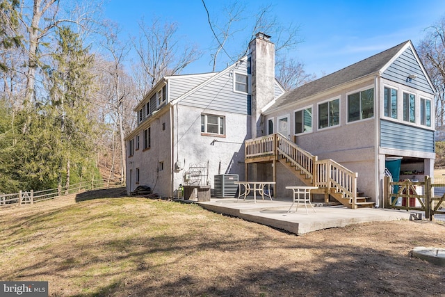 rear view of house featuring stucco siding, fence, stairway, a chimney, and a patio area