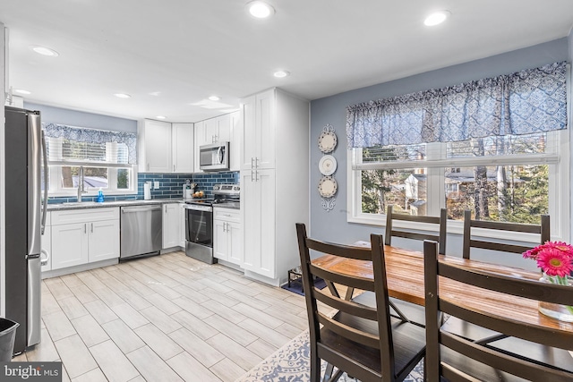 kitchen featuring recessed lighting, stainless steel appliances, white cabinets, and decorative backsplash