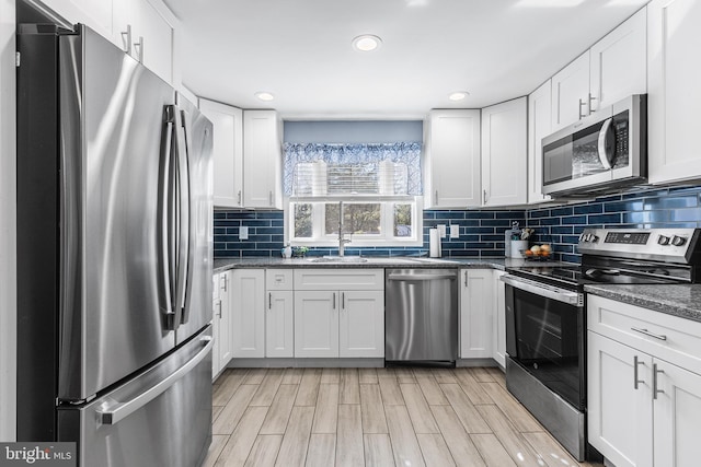 kitchen with white cabinetry, a sink, tasteful backsplash, and stainless steel appliances