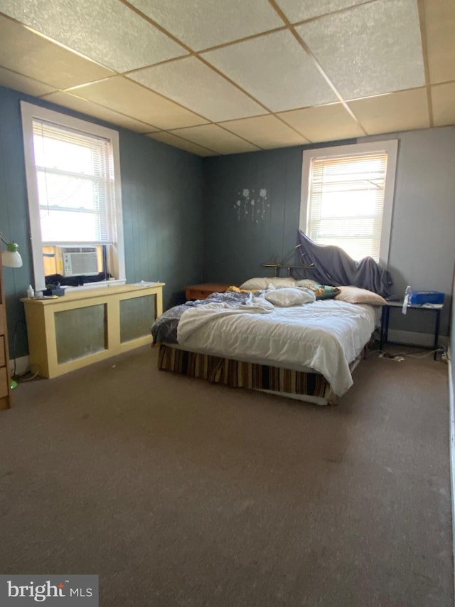 carpeted bedroom featuring a paneled ceiling, multiple windows, and cooling unit