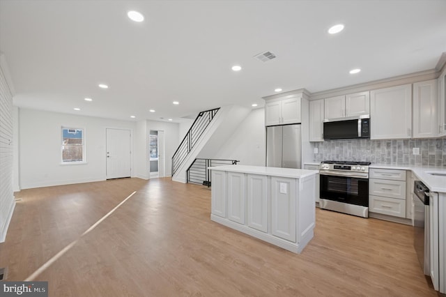 kitchen with visible vents, a kitchen island, light countertops, light wood-style floors, and appliances with stainless steel finishes