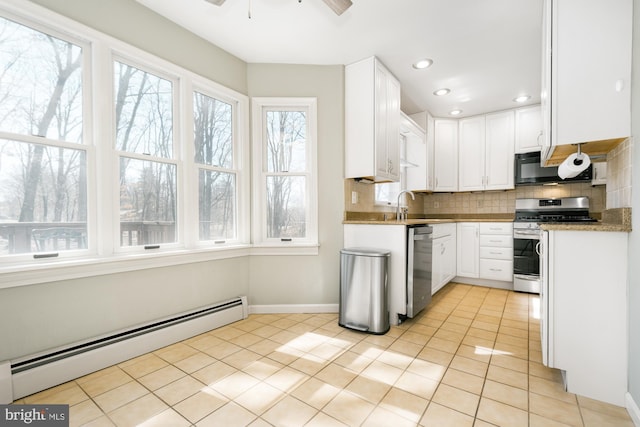 kitchen featuring baseboard heating, decorative backsplash, light tile patterned flooring, stainless steel appliances, and a sink