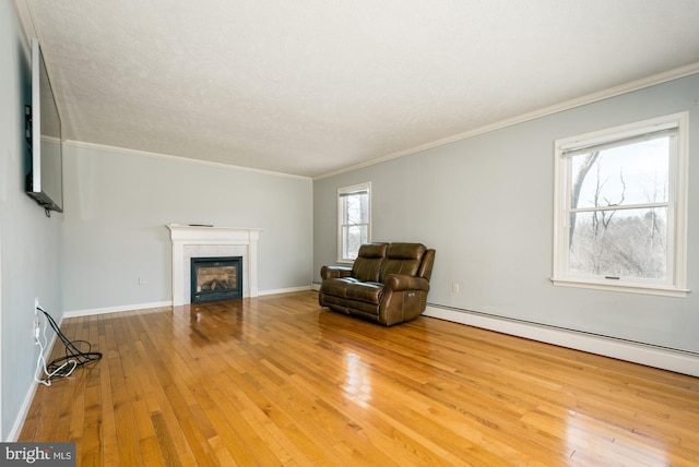 living area with ornamental molding, a tiled fireplace, hardwood / wood-style floors, baseboards, and baseboard heating