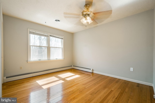 empty room featuring baseboards, visible vents, wood-type flooring, and a baseboard radiator