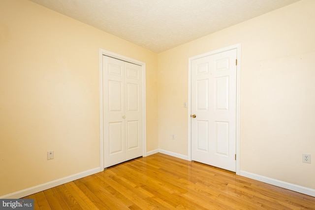 unfurnished bedroom with a closet, baseboards, and light wood-style floors