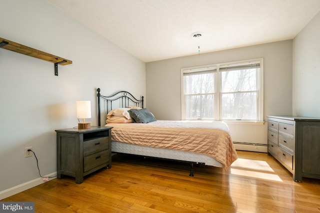 bedroom featuring baseboards, visible vents, light wood finished floors, and a baseboard radiator