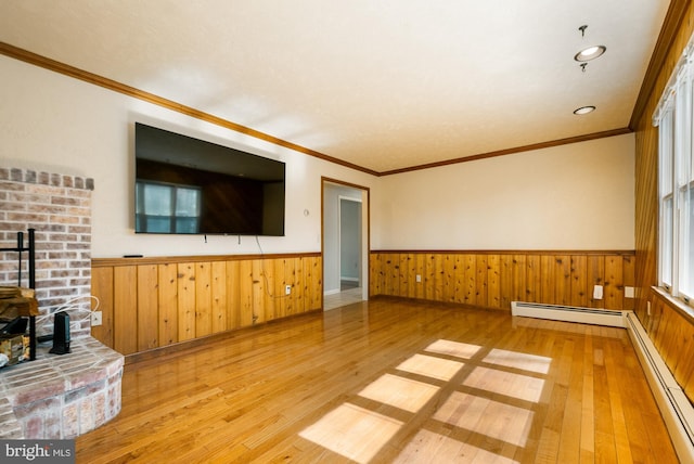 unfurnished living room featuring a wainscoted wall, a baseboard heating unit, a wood stove, and a baseboard radiator