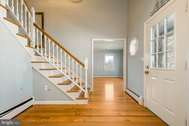 foyer featuring stairs, wood finished floors, and baseboard heating