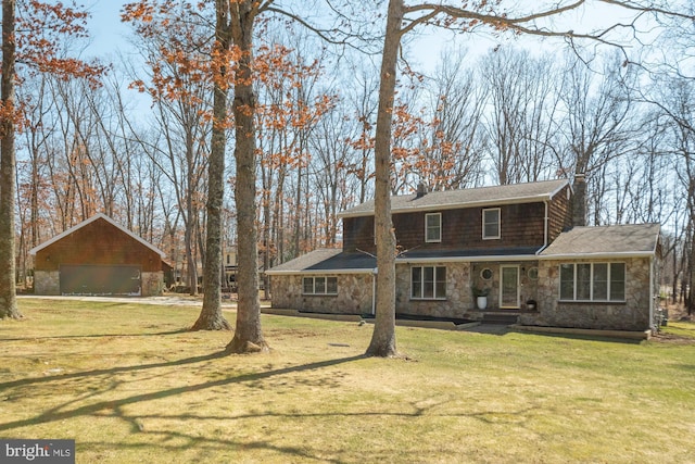 rear view of house featuring stone siding, an outdoor structure, and a yard