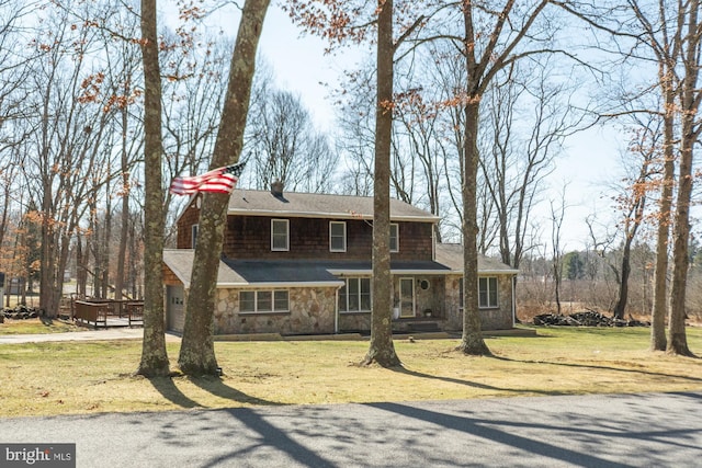 view of front of home with stone siding, covered porch, a chimney, and a front lawn