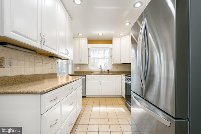 kitchen featuring white cabinets, light tile patterned flooring, appliances with stainless steel finishes, and a sink