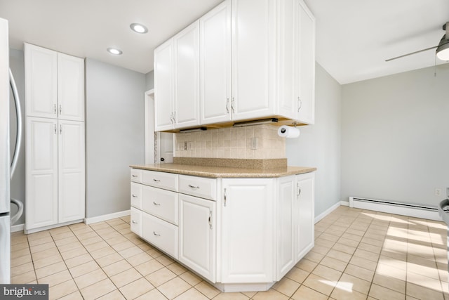 kitchen featuring decorative backsplash, white cabinets, light countertops, and a baseboard radiator