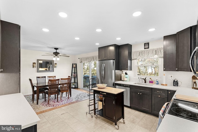 kitchen with recessed lighting, a sink, light countertops, appliances with stainless steel finishes, and backsplash