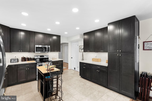 kitchen featuring decorative backsplash, light countertops, recessed lighting, and appliances with stainless steel finishes