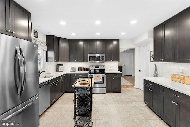 kitchen featuring a sink, backsplash, recessed lighting, stainless steel appliances, and light countertops