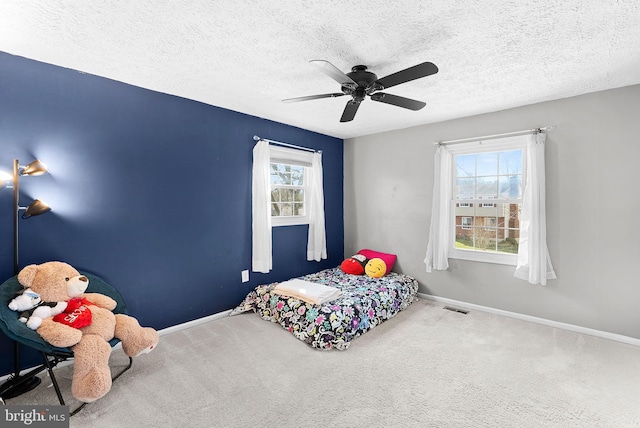 carpeted bedroom with a ceiling fan, baseboards, visible vents, and a textured ceiling